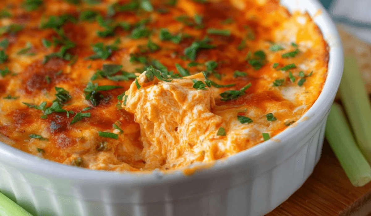 Buffalo Chicken Dip in a white dish with melted cheese and parsley