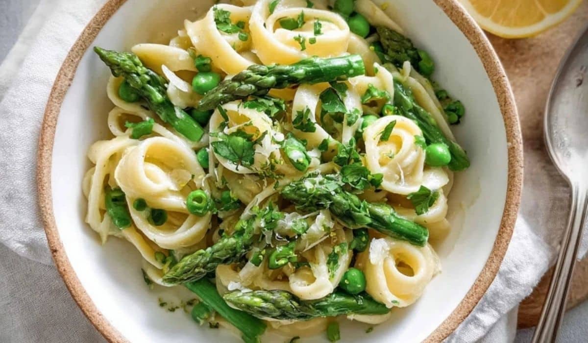 Creamy asparagus pasta with green peas in a white bowl