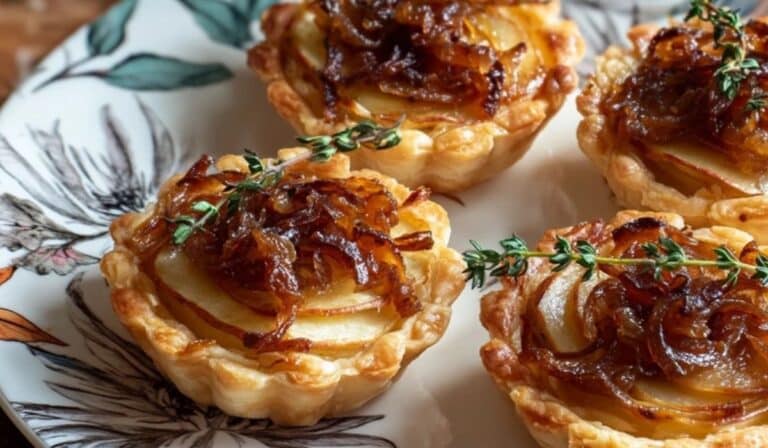 Caramelized Onion and Apple Tartlets on a ceramic plate with thyme garnish
