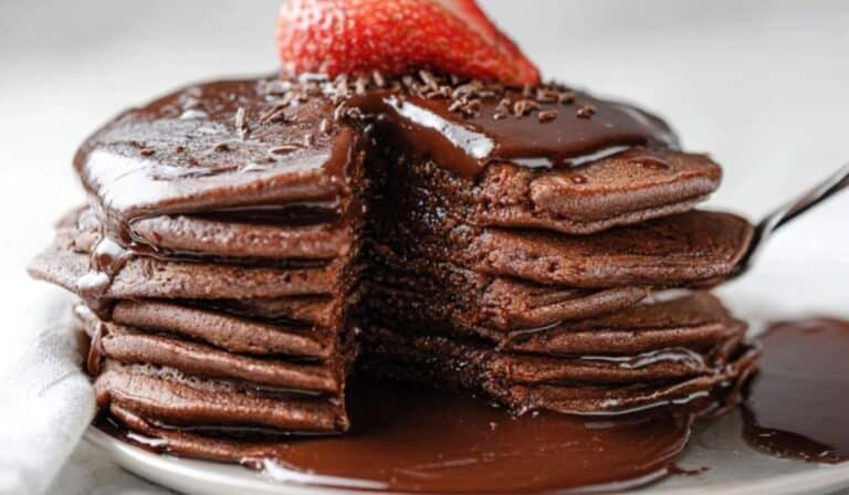 Fluffy chocolate pancakes stacked high with strawberry on top