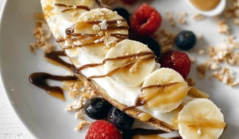 Breakfast Banana Split with sliced banana, creamy yogurt, berries, and chocolate drizzle