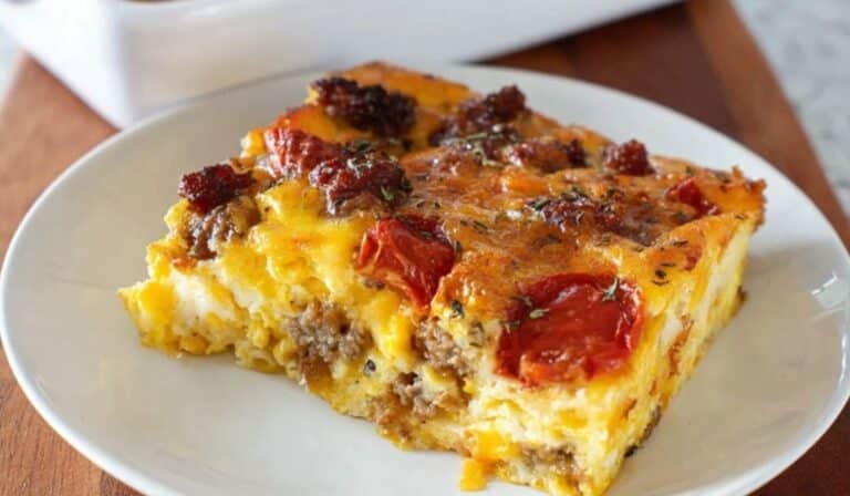 Chorizo and Egg Breakfast Casserole slice with melted cheese and tomato topping