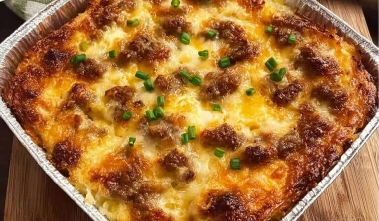 Sausage, Egg and Cream Cheese Hashbrown Casserole in a foil tray with golden brown top and melted cheese.