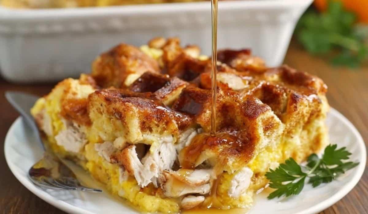 Chicken and Waffles Casserole topped with maple syrup served on a white plate. Caption: