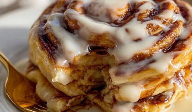 Stack of cinnamon roll pancakes drizzled with cream cheese glaze