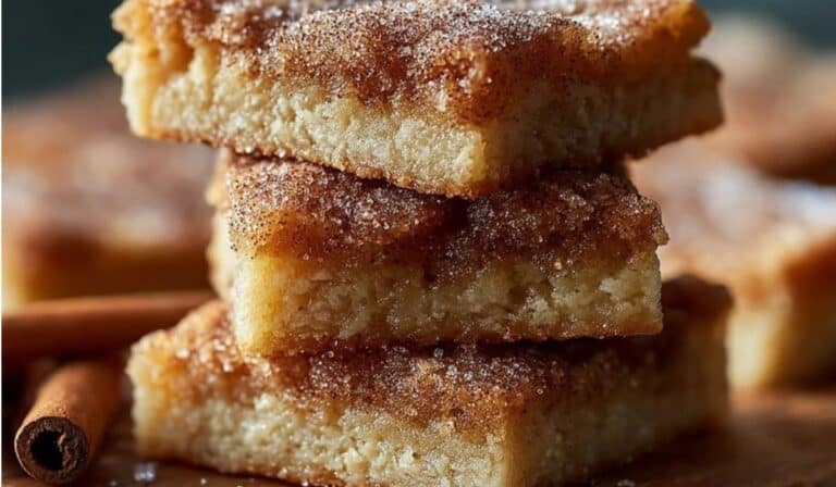 Easy Cinnamon Sugar Blondies stacked on a wooden plate with cinnamon sugar topping