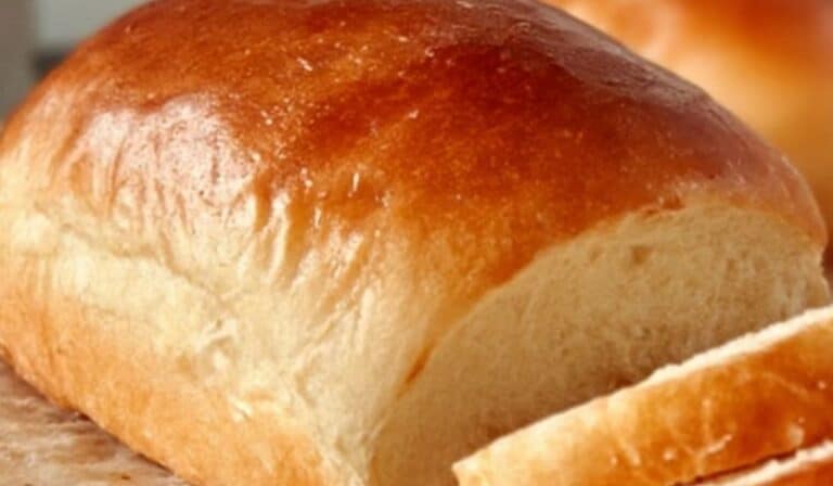 Freshly baked No-Fail Amish White Bread loaf sliced on parchment paper