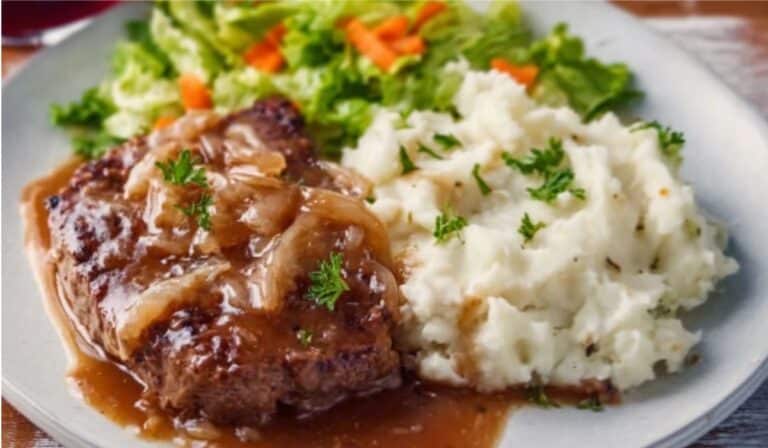 Easy cube steak in skillet with onion gravy over mashed potatoes