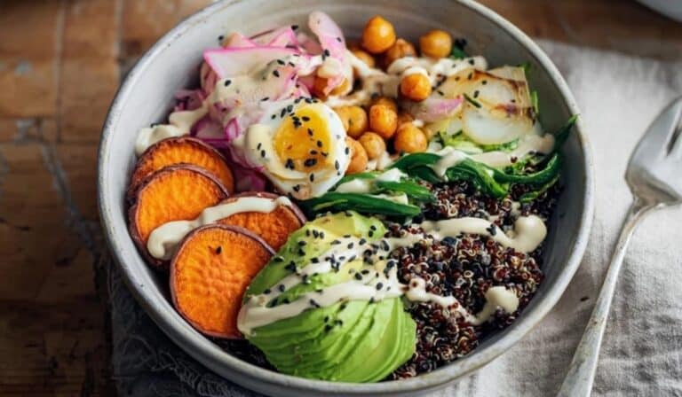 Fermented veggie power bowl with quinoa, roasted veg, kimchi and sauerkraut in a cozy Dinner setting