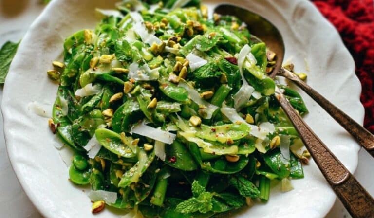 Fresh snap pea salad with mint in a white bowl with feta and almonds