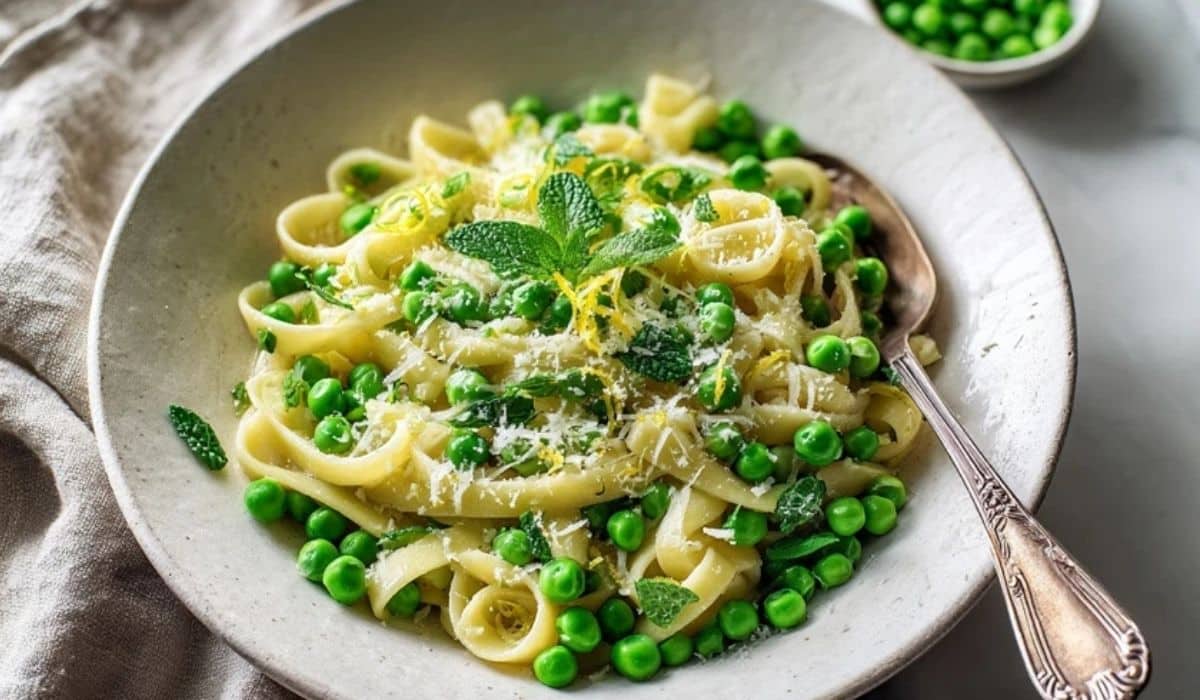 Pea and mint pasta side in a white bowl with lemon zest and parmesan