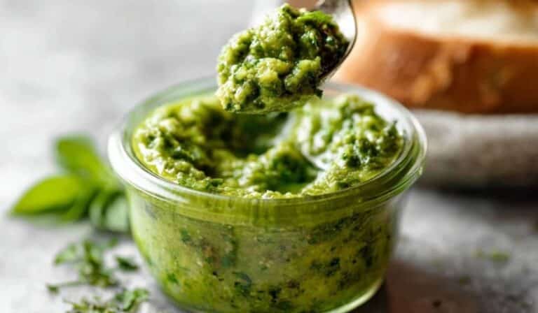 Spring herb pesto 5 ways in a bowl with fresh herbs and lemon