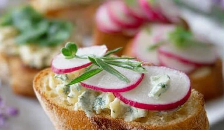 Spring radish and butter crostini on a platter with herbs and flaky salt