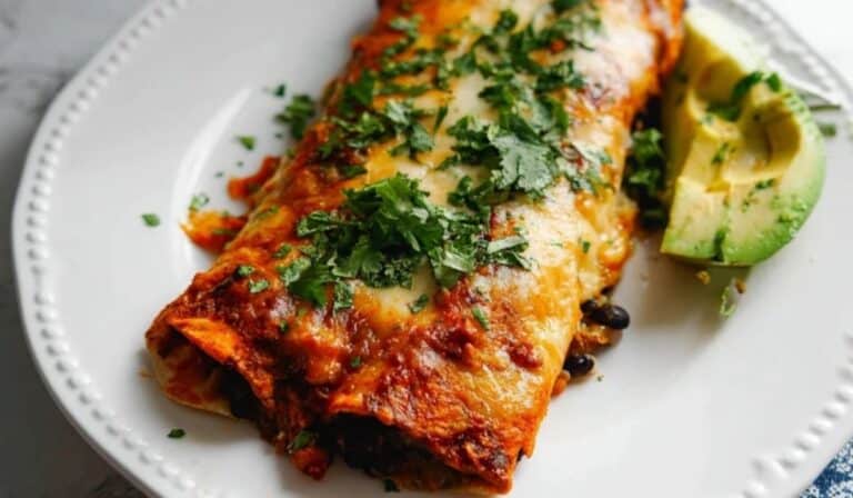 Vegan black bean enchiladas baked in red sauce with cilantro and avocado